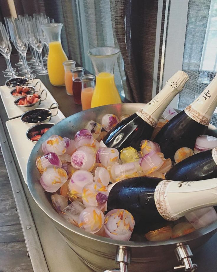 several bottles of champagne are in an ice bucket on the counter next to orange juice