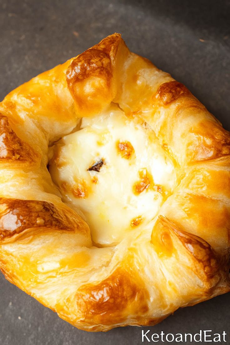 a close up of a pastry with cheese in it's center on a table