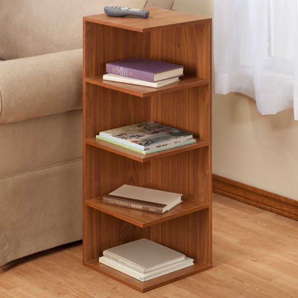 a book shelf with books and a remote control on top of it next to a couch