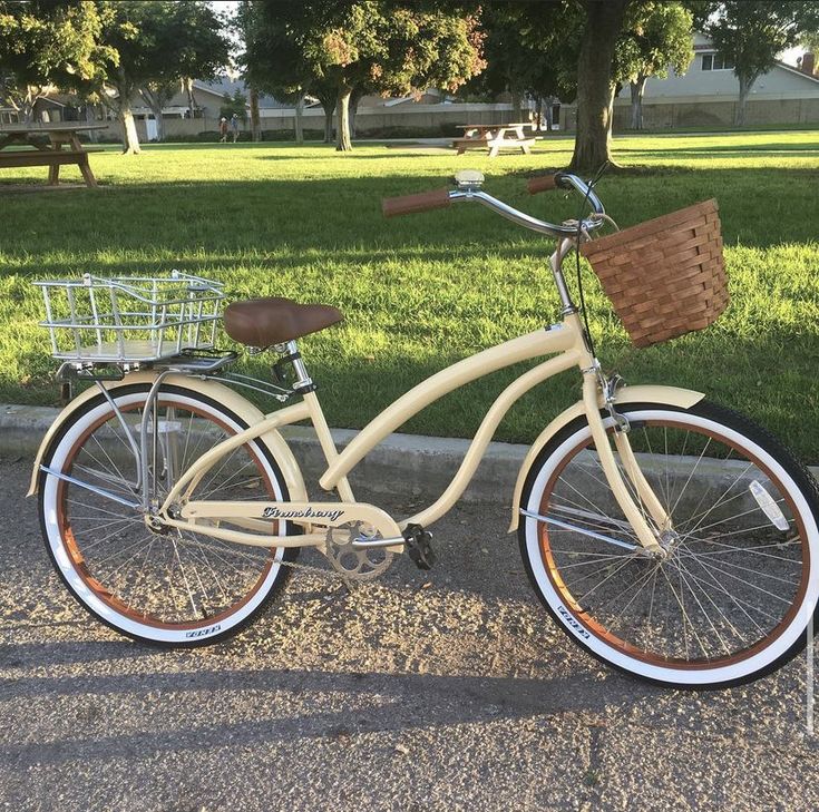 a white bicycle parked on the side of a road next to a grass covered park