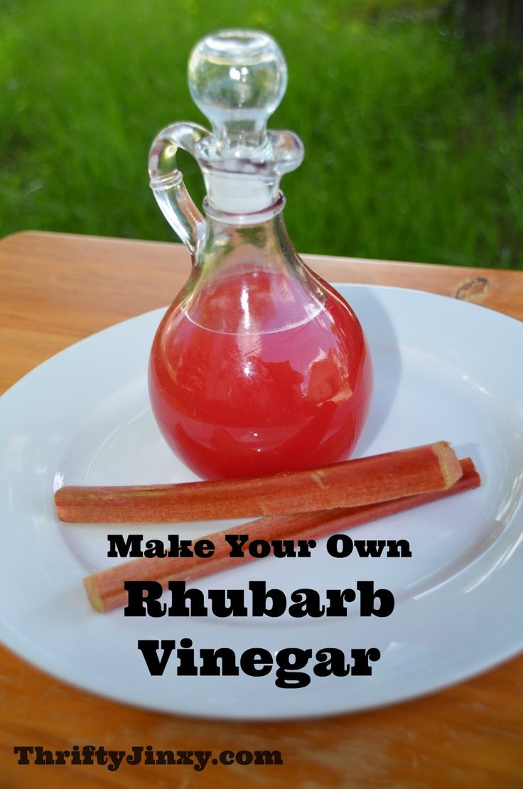 a bottle of rhubarb wine next to some cinnamon sticks on a plate