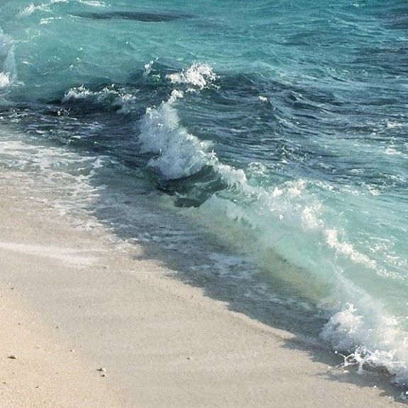 there is a wave coming in from the ocean onto the beach and it's white sand