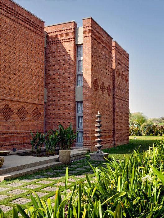 the building is made out of bricks and has many plants growing in front of it