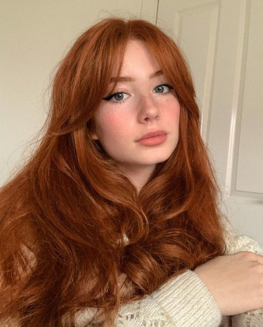 a woman with long red hair is posing for the camera