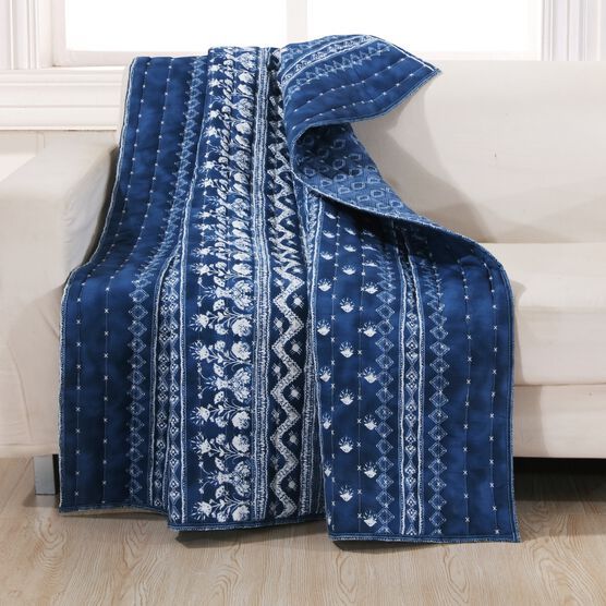 a blue blanket sitting on top of a white couch