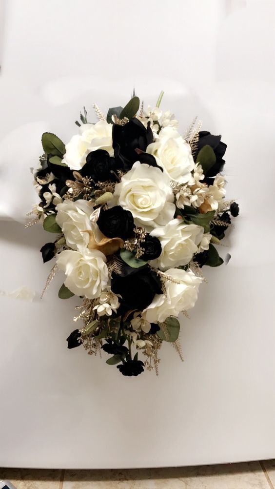 a bouquet of white and black flowers sitting on top of a table