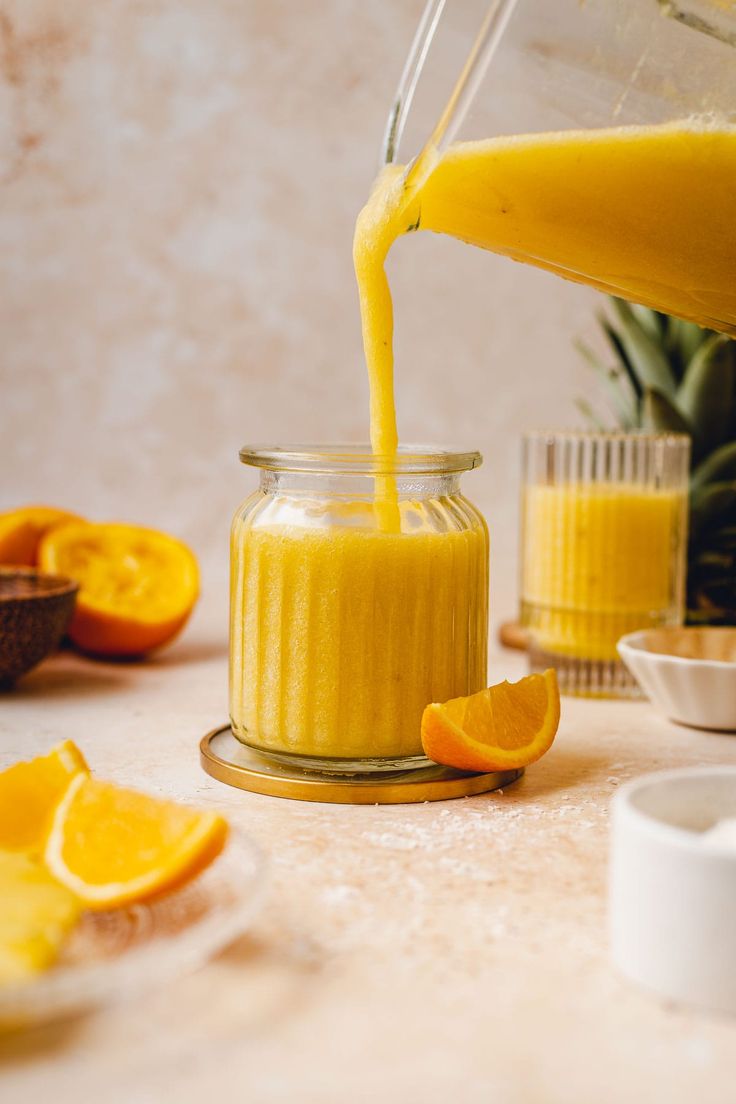 someone is pouring orange juice into a jar