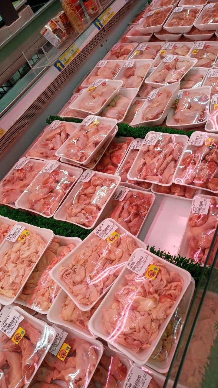 several trays of meat are on display in a grocery store