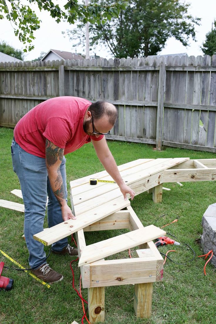 a man working on a wooden bench in the yard