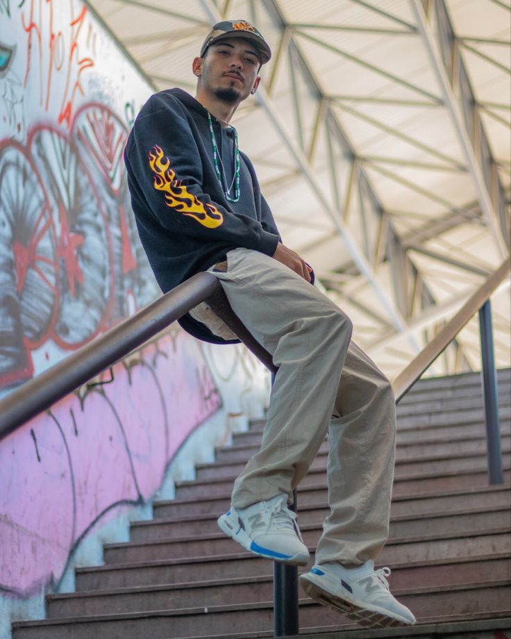 a man sitting on top of a stair rail next to graffiti covered walls and stairs