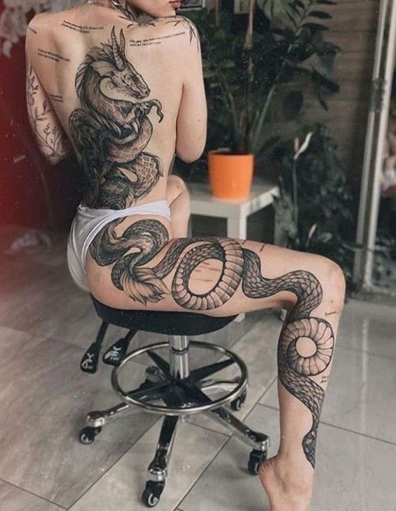 a woman sitting on top of a chair with tattoos on her back and legs,