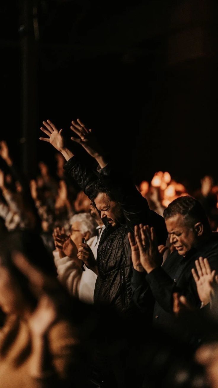 a group of people standing next to each other with their hands up in the air