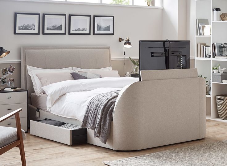 a bed sitting in a bedroom next to a desk with a computer on top of it