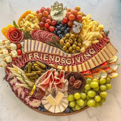 a platter filled with lots of different types of cheese and meats on top of a marble counter