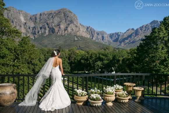 a bride standing on a balcony with mountains in the background