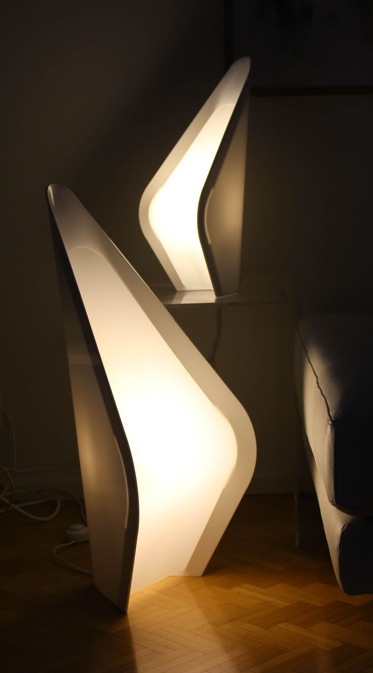 two modern lamps sitting next to each other on a wooden floor