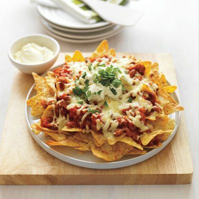 a white plate topped with nachos covered in cheese and sauce