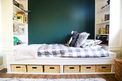 there is a bed with drawers under it and a green wall in the back ground