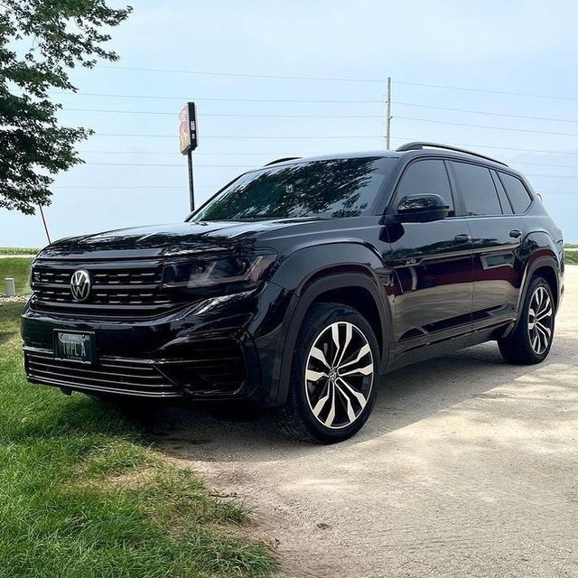 the front end of a black volkswagen suv parked on a dirt road next to a tree