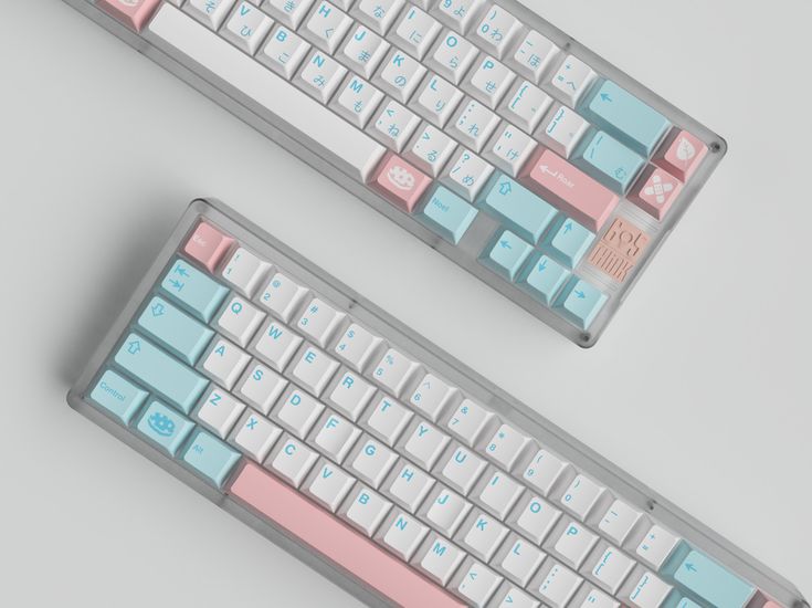 two pink and blue keyboards sitting next to each other on a gray surface with white keys