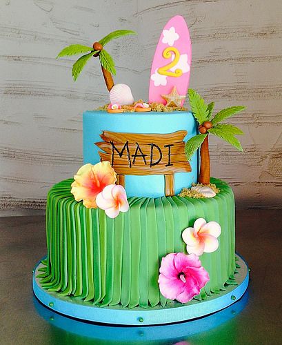 a birthday cake decorated with surfboards and flowers