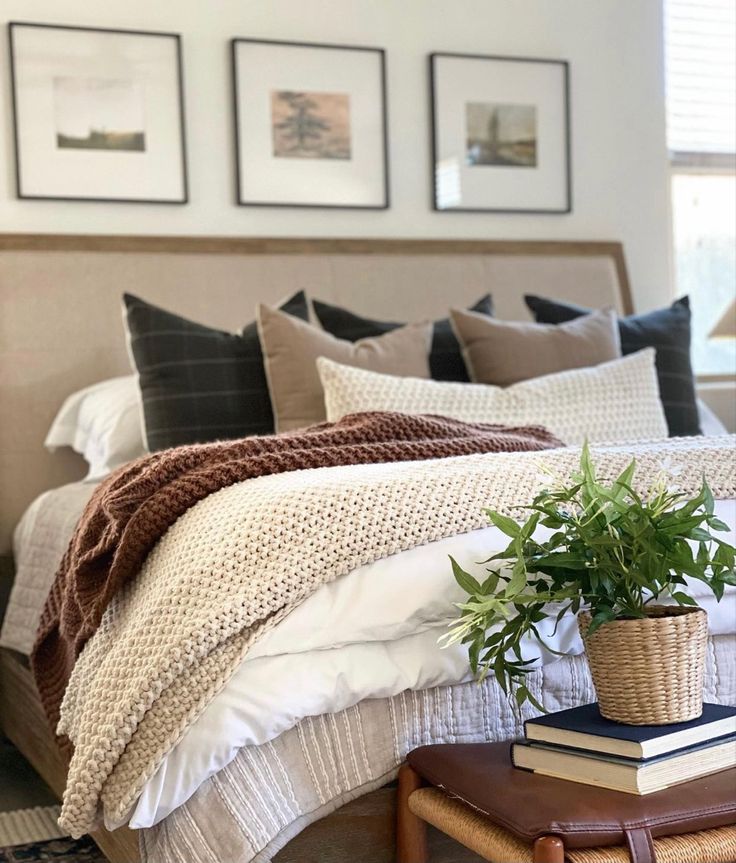 a bed with pillows and blankets on top of it next to a plant in a basket