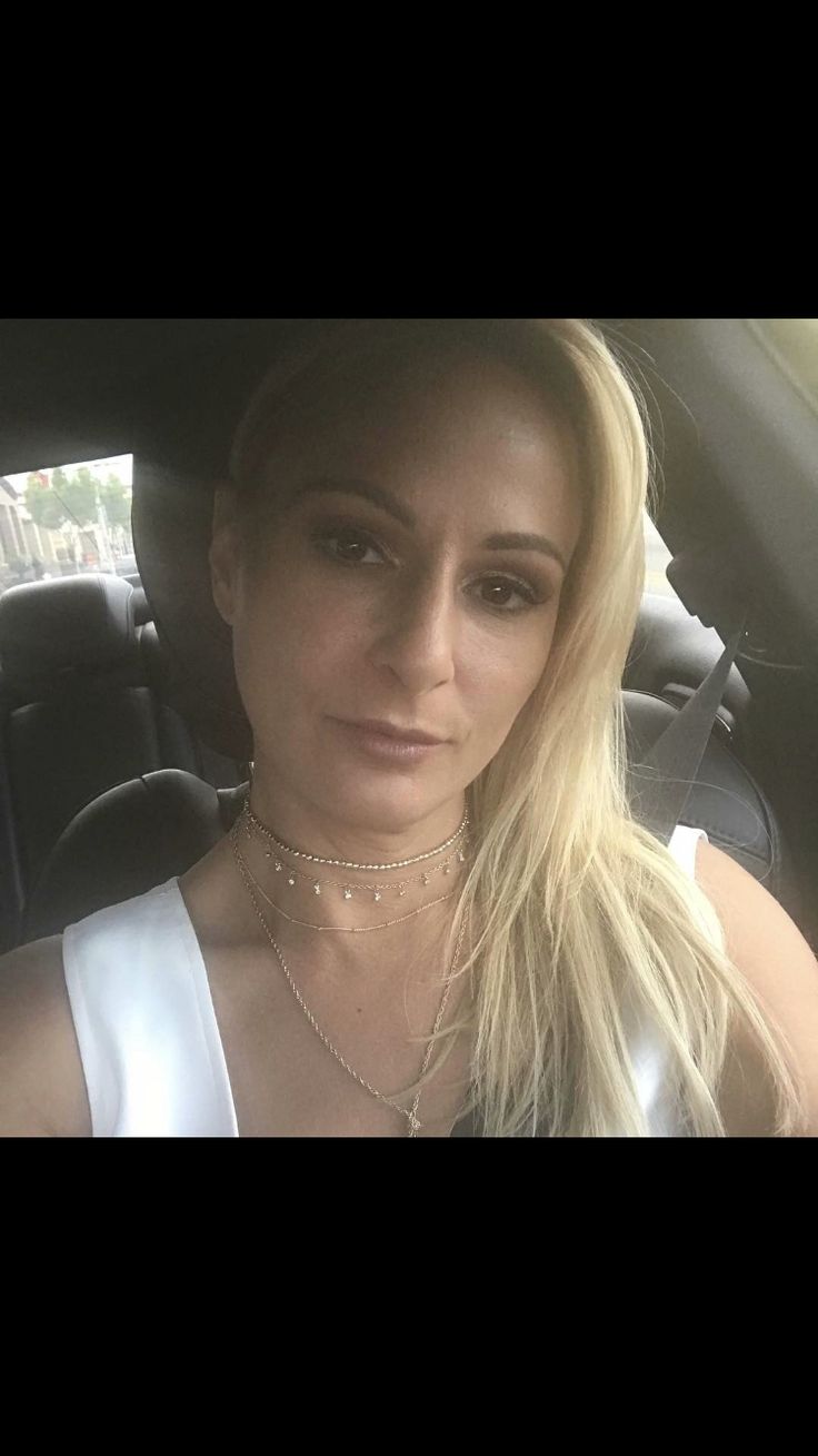 a woman sitting in the back seat of a car wearing a silver dress and necklace