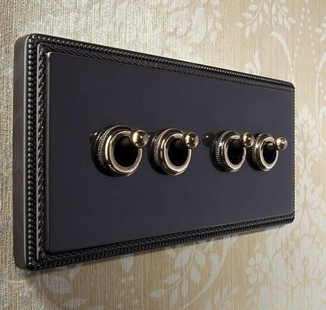 a black and gold wall mounted switch plate with three knobs on the back of it