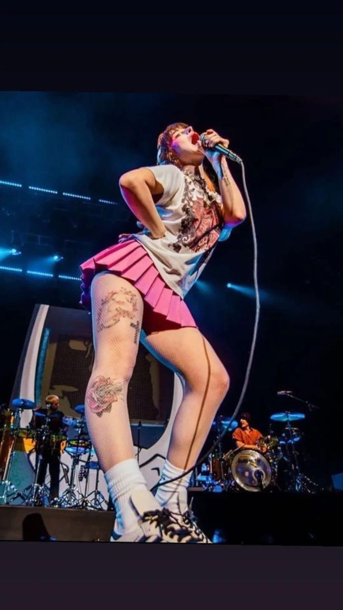 a woman on stage with her legs crossed and holding a microphone in front of her