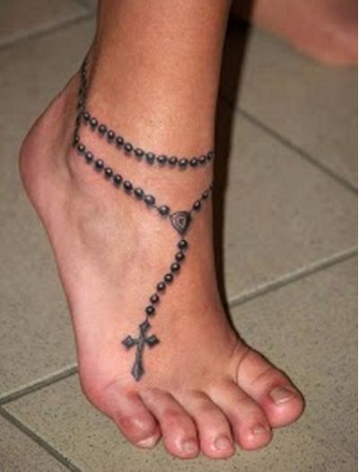 a woman's foot with a rosary and cross tattoo on the side of it