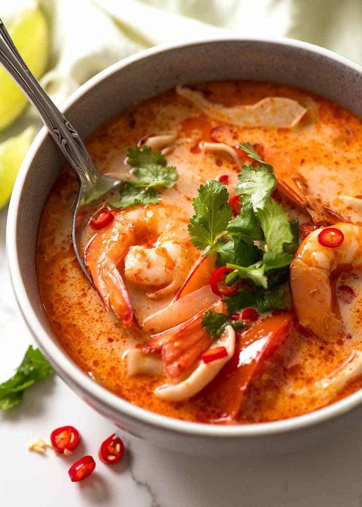 a bowl of soup with shrimp and cilantro garnish