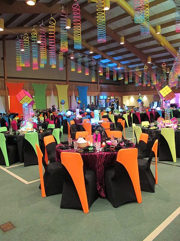 a banquet hall with tables and chairs decorated in neon colors