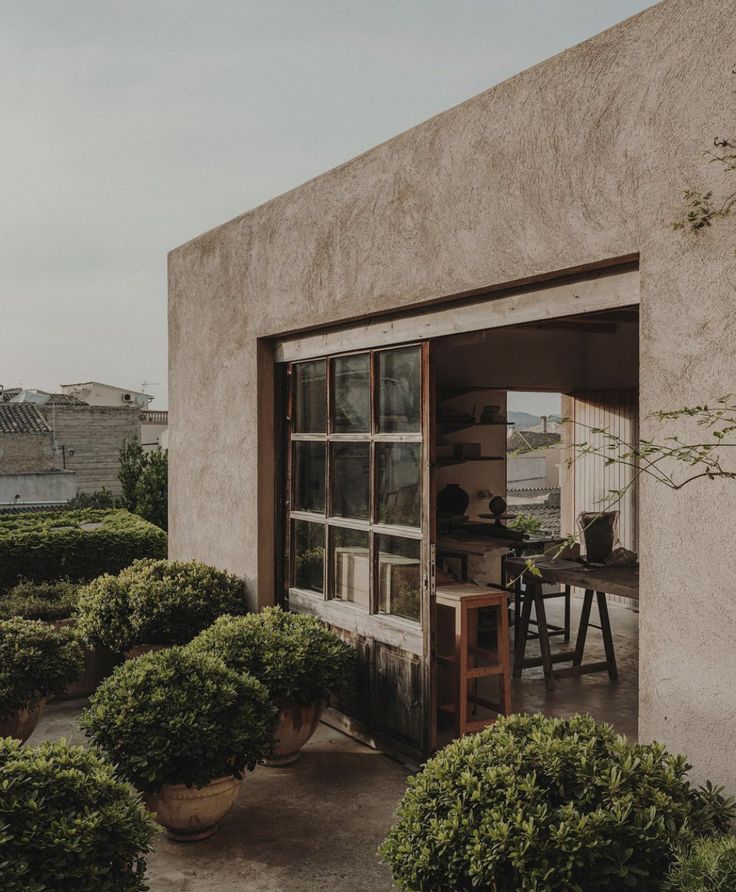 an open door leading to a patio area with potted plants and tables in it