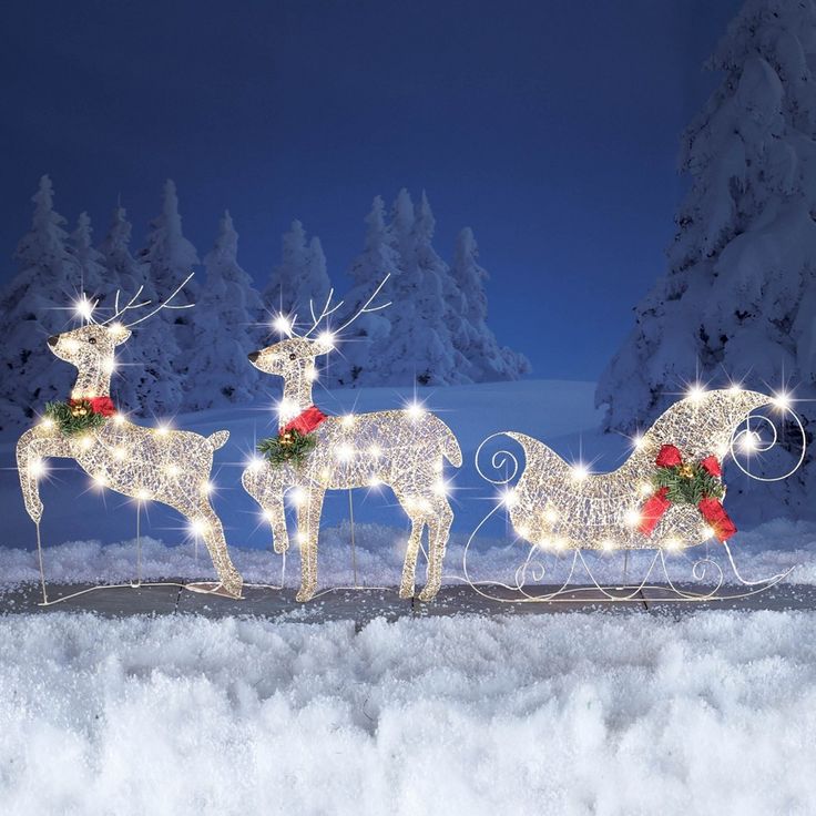 three lighted reindeers are standing in the snow with their sleigh lights on