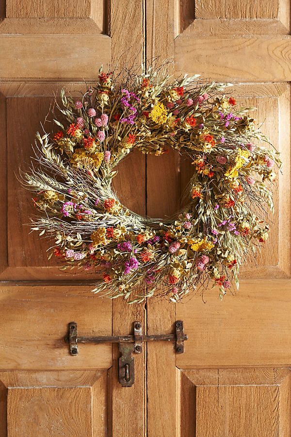 a wreath hanging on the front door of a house with flowers all over it's frame