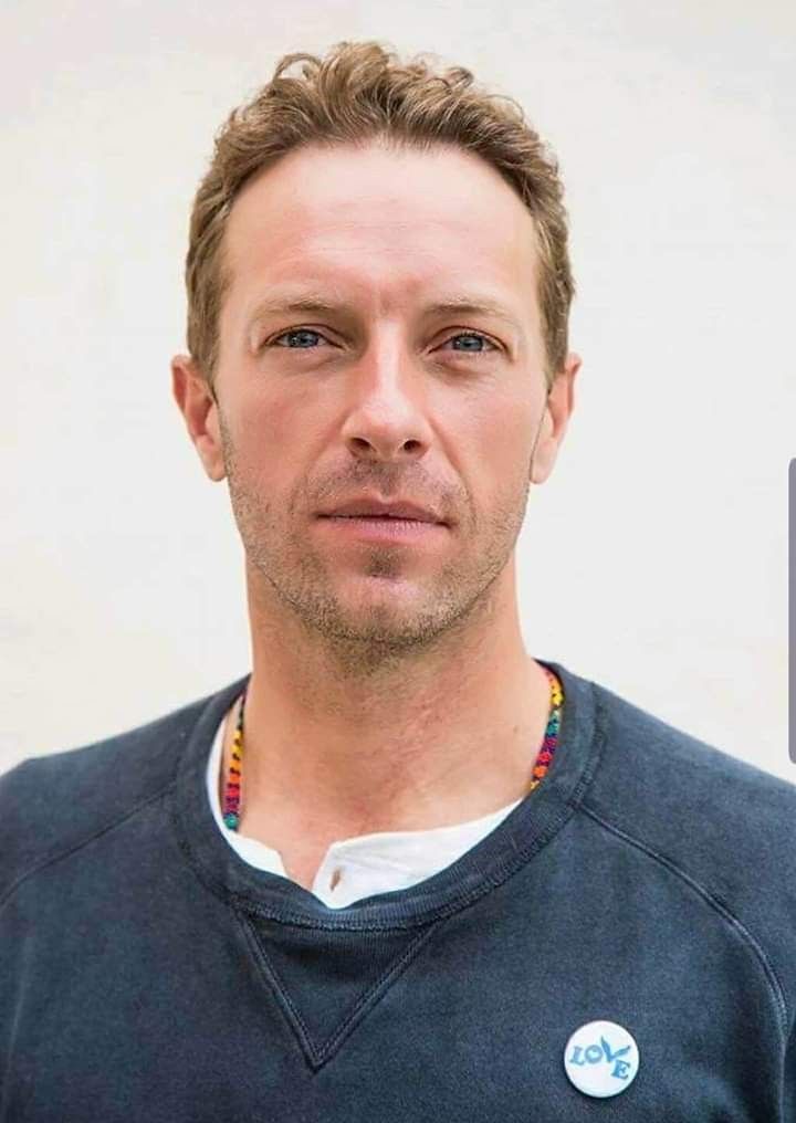 a man in a black shirt is looking at the camera with a serious look on his face