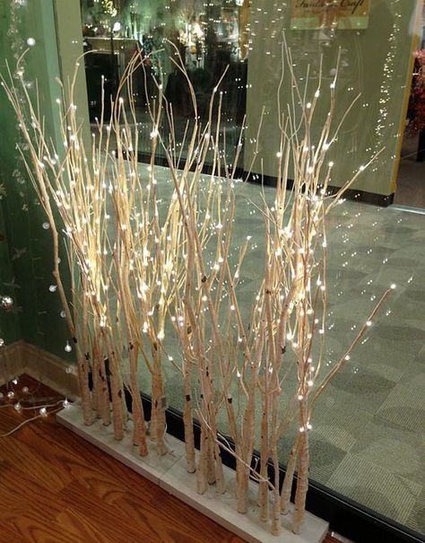 some white branches with lights on them in front of a window