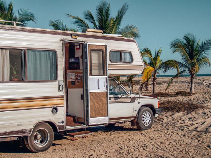 an rv parked on the beach with palm trees in the background