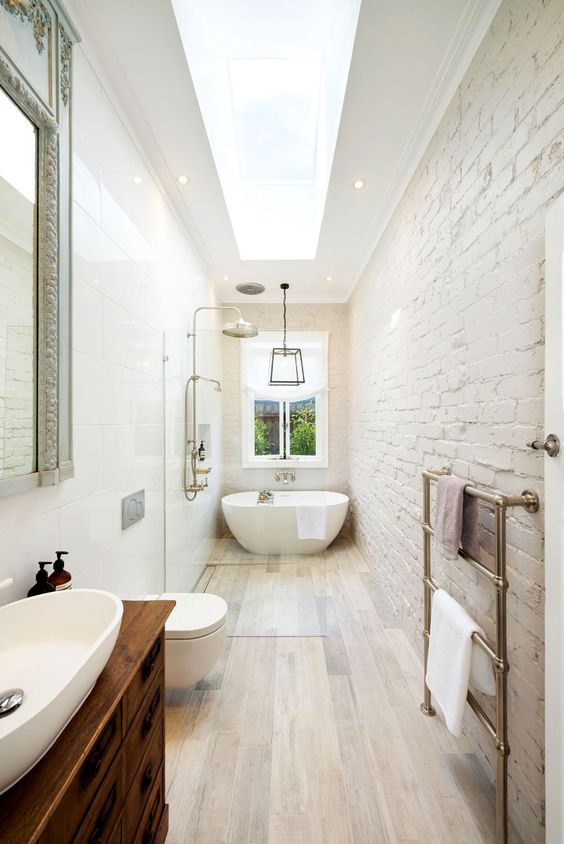 a large bathroom with a skylight above the bathtub and sink, is shown