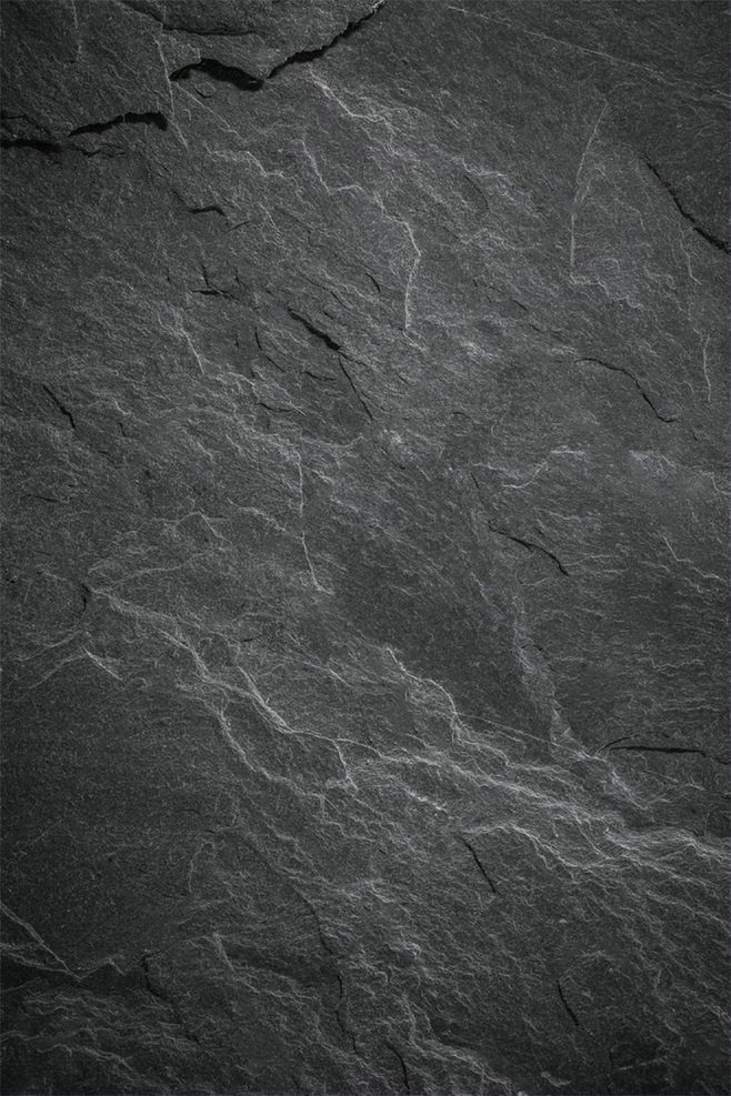 black and white photograph of rocks with cracks in the rock face, taken from above