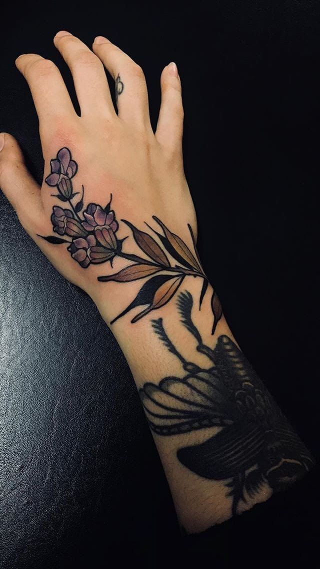 a woman's hand with flowers on it and a black bird in the middle