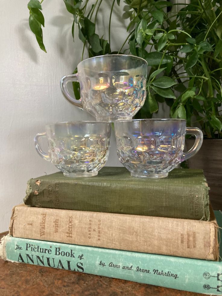 three glass cups sitting on top of books