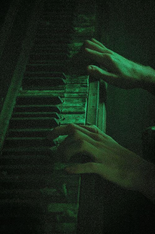 two hands are playing the piano with green light on it's sides and black background