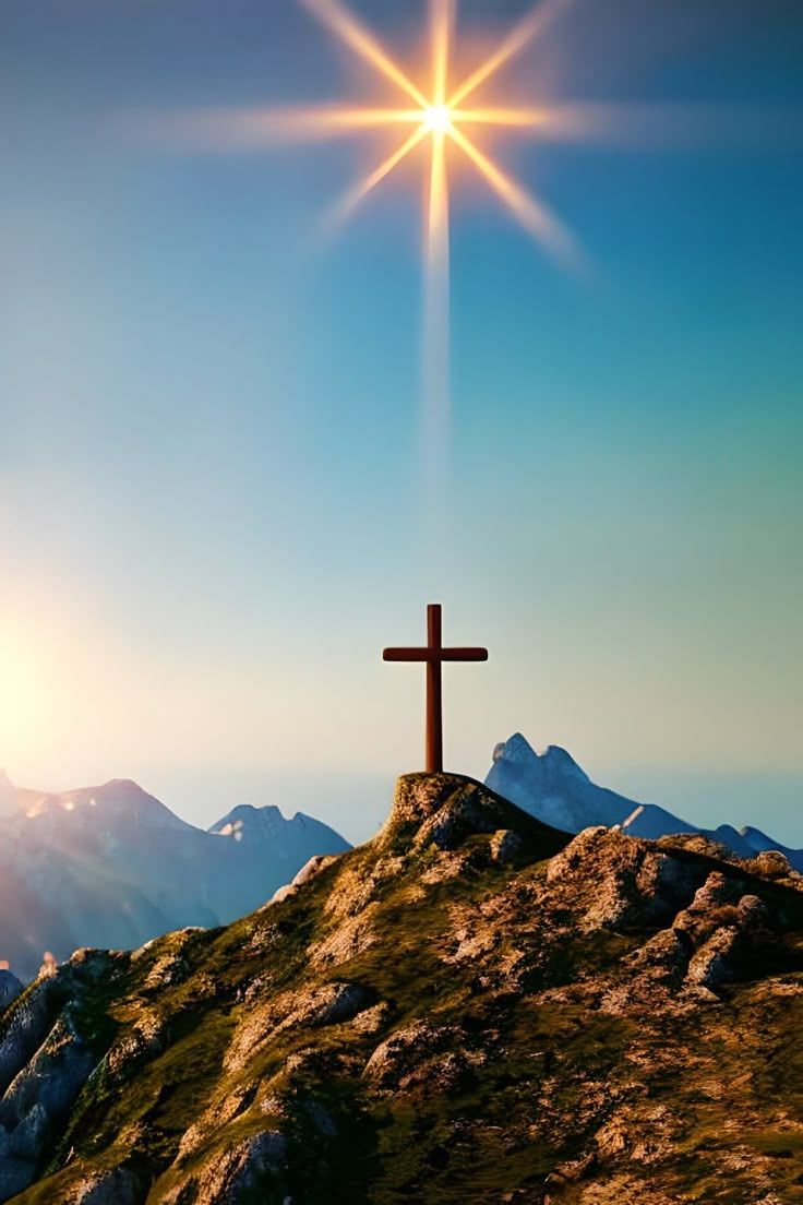 a cross on top of a hill with the sun shining down over mountains in the background