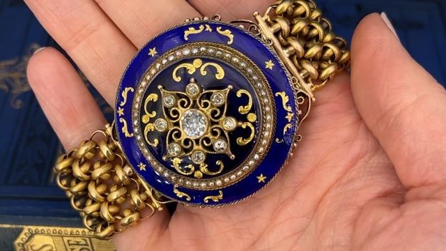 This antique bracelet features a Victorian era 10K yellow gold diamond and pearl domed setting (converted from a brooch) accented with blue enamel and gold accents. The bracelet is accented with nine (9) old European/old mine cut diamonds and fifty-two (52) seed pearls. The seed pearls measure an average of 1.7mm. The 14K yellow gold fancy mesh link bracelet measures 25mm wide and 6.1mm thick. The bracelet measure an overall length of 7 inches and is finished with a hidden box clasp. The bracelet has natural patina and light enamel loss. It fits up to a 6.5 inch wrist. Antique Bracelets, Yellow Gold Bracelet, Seed Pearl, European Cut Diamonds, June Birth Stone, Gold Accents, Victorian Era, High Quality Jewelry, Estate Jewelry