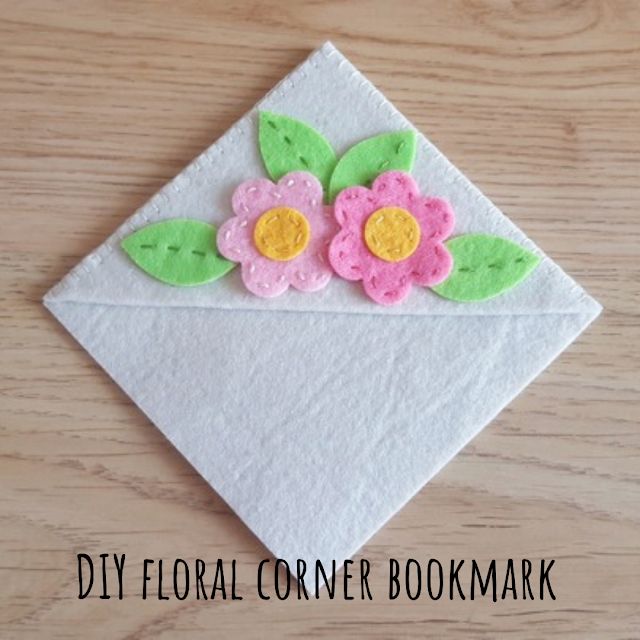 an origami flower is on top of a white envelope with green leaves and pink flowers