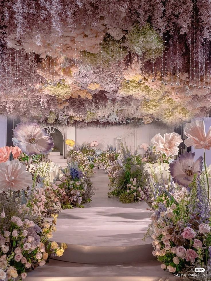 an outdoor wedding ceremony with pink flowers and greenery on the ceiling, surrounded by hanging chandeliers