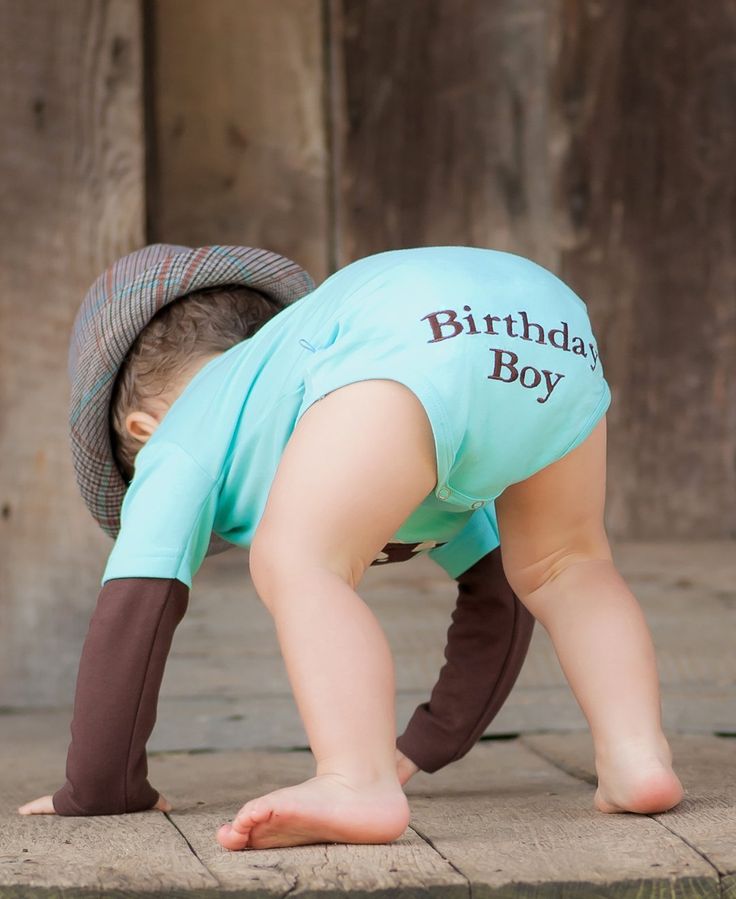 a small child wearing a blue shirt and brown pants is bending down to pick up something from the ground