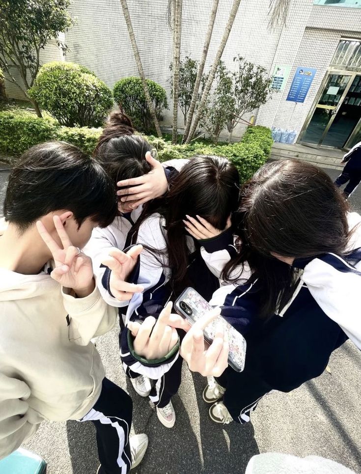 a group of young people standing next to each other in front of a building with their hands together