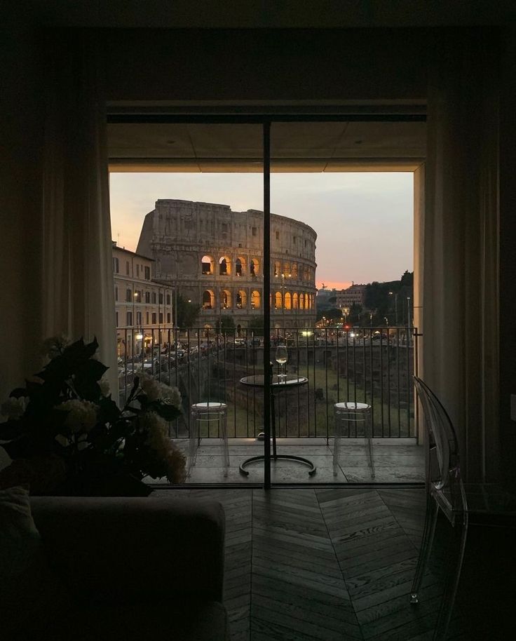 an open window with the view of a roman colossion at sunset in rome, italy